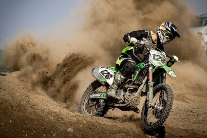 Green dirt bike throwing dirt