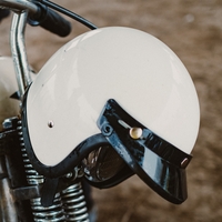 three-quarter helmet hanging on motorcycle handlebar